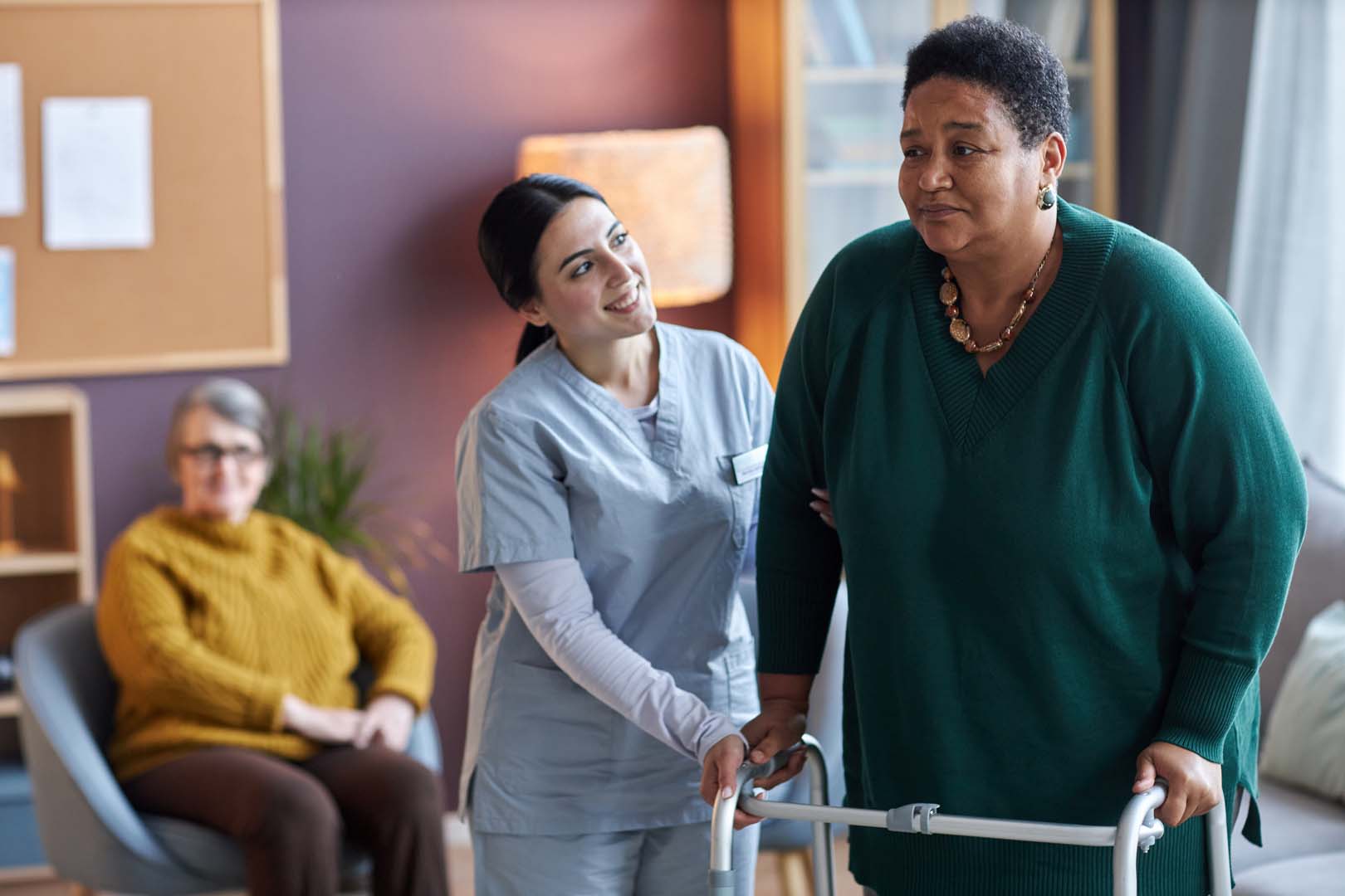 A nurse helping a senior woman using a mobility walker